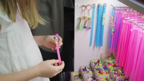 Маленькая девочка печатает свое имя из букв бусин на браслете — стоковое видео