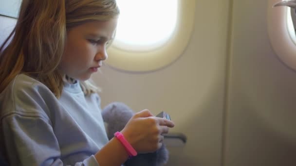 A little girl plays her phone while flying on a plane. — Stock Video