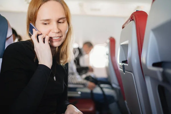 Kvinnan pratar i telefon på en plats ombord på planet. wifi för passagerare — Stockfoto