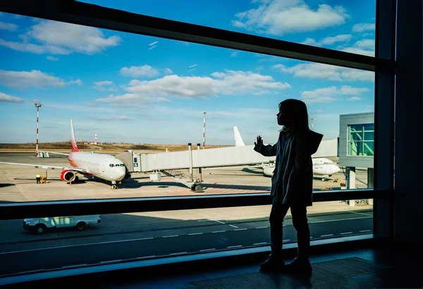 Una niña silueta de pie junto a la ventana en el aeropuerto. — Foto de Stock