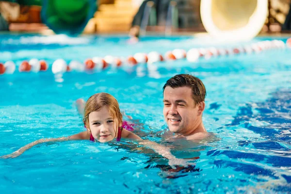 Papá enseña a su hija a nadar en la piscina. entrenamiento de natación. — Foto de Stock