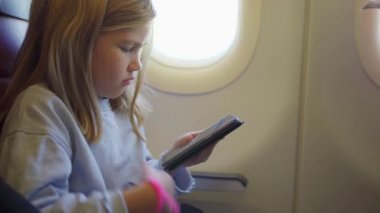 Küçük bir kız uçakta uçarken telefonunu çalıyor..