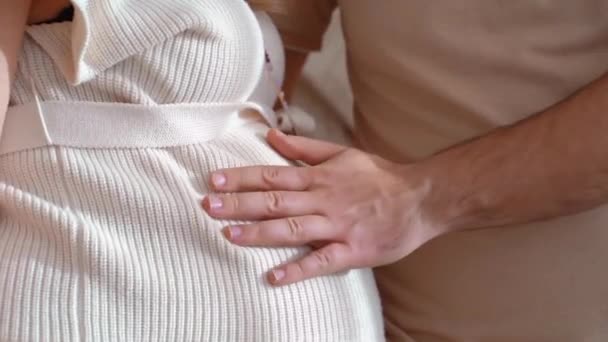 Una mano de hombre toca el abdomen de una mujer embarazada con sus dedos. — Vídeo de stock