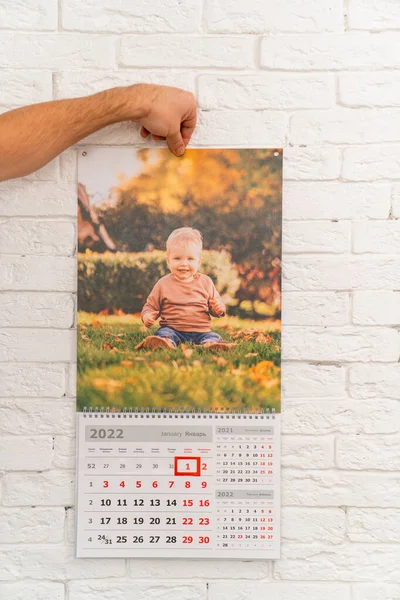 Mens mano tiene calendario con foto di bambino di fronte. prodotti stampati — Foto Stock