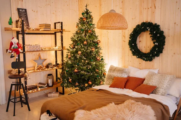 Decoración de año nuevo para el dormitorio. Árbol de Navidad en el dormitorio por cama con corona en la pared — Foto de Stock