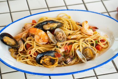 Ekoseli masa örtüsüyle oval tabakta deniz mahsullü spagetti.. 