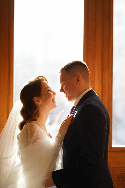 Silhouetten von Braut und Bräutigam im Sonnenlicht durch das Glas in der Tür. — Stockfoto