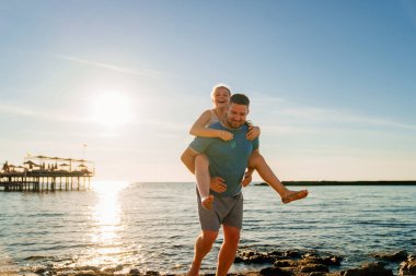 Babası deniz kıyısında kızına biniyor.. 