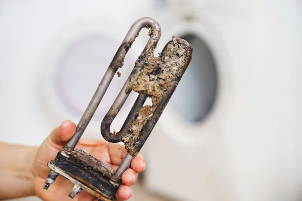 Reparación de lavadora. en la mano viejo calentador eléctrico tubular — Foto de Stock