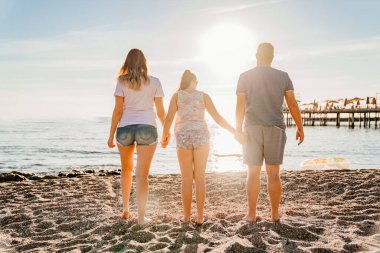 Dikiz aynası. Deniz kıyısında güneş ışığı altında bir aile. Tatil köyünde aile tatilleri.