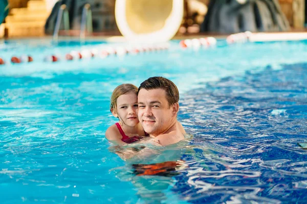Papá y su hija se abrazan y nadan en la piscina. entrenamiento de natación. — Foto de Stock