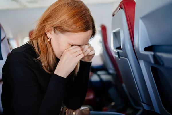 En sömnig kvinna gnider ögonen med händerna i en flygplansstol. långa flygningar. — Stockfoto