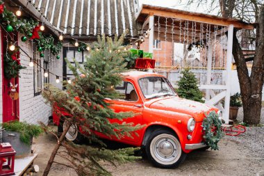 Evin verandasında Noel çelengi olan kırmızı küçük bir araba.. 