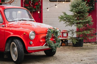 Evin verandasında Noel çelengi olan kırmızı küçük bir araba.. 