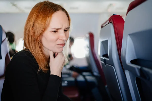어느 추운 여인 이 비행기를 타고 위독 한 목구멍으로 기침을 한다. — 스톡 사진