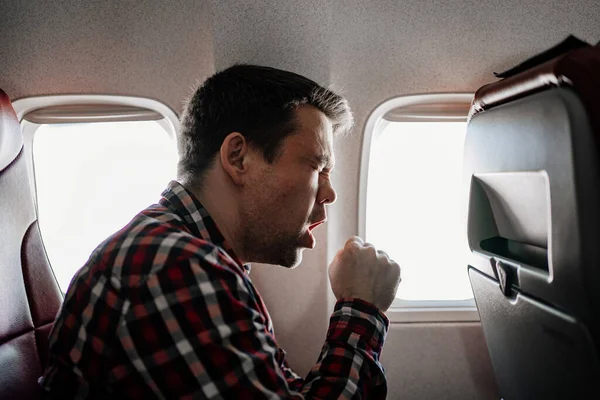 Ekose gömlekli bir adam pencerede öksürüyor.. 