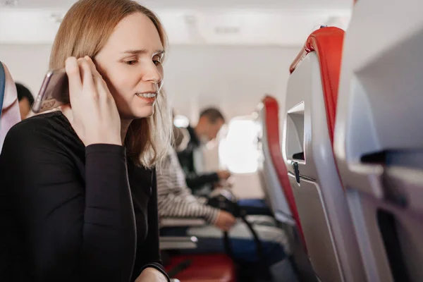Kvinna lyssnar på ett röstmeddelande på telefonen i en plats ombord på planet. — Stockfoto
