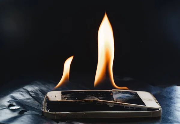 Bruciando smartphone rotto su uno sfondo nero. — Foto Stock