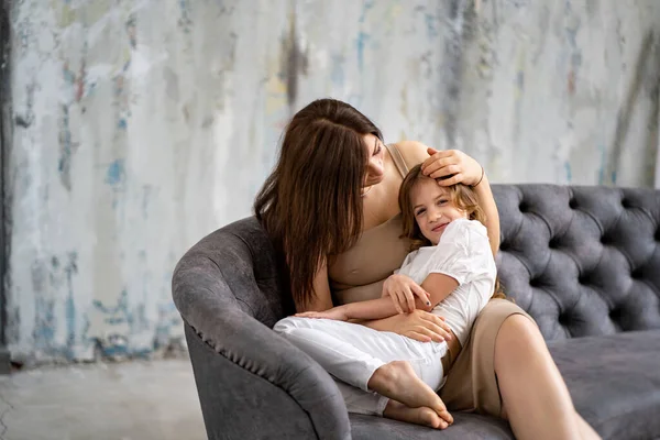 Anne kanepede kızına sarılıyor. Mutlu aile. 