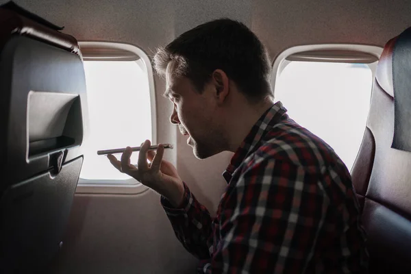 Hombre speakerphone llamada en el teléfono en el asiento del pasajero a bordo del avión. — Foto de Stock