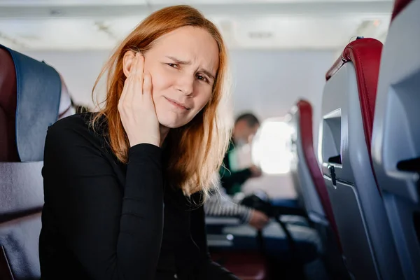 En kvinna på ett flygplan har huvudvärk och öronvärk när hon flyger på ett flygplan — Stockfoto