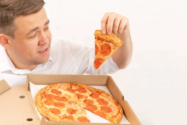 A man in a white shirt holds a slice of pizza with sausage. food delivery — Stock Photo, Image