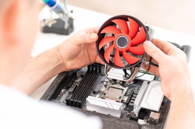 Bilgisayar atölyesi. Elinde soğutucuyla tamirci.