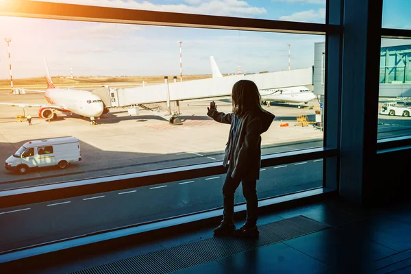 Una niña silueta de pie junto a la ventana en el aeropuerto. — Foto de Stock