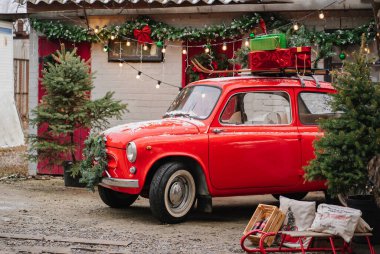 Evin verandasında Noel çelengi olan kırmızı küçük bir araba.. 