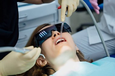 Gerçek. Diş hekimi hastaya bakıcı, diş matkabı ve dolgu malzemesi veriyor.