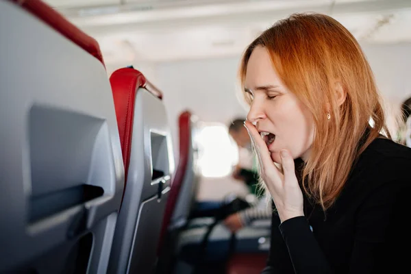 一个困倦的女人在飞机座位上打呵欠。长途飞行. — 图库照片
