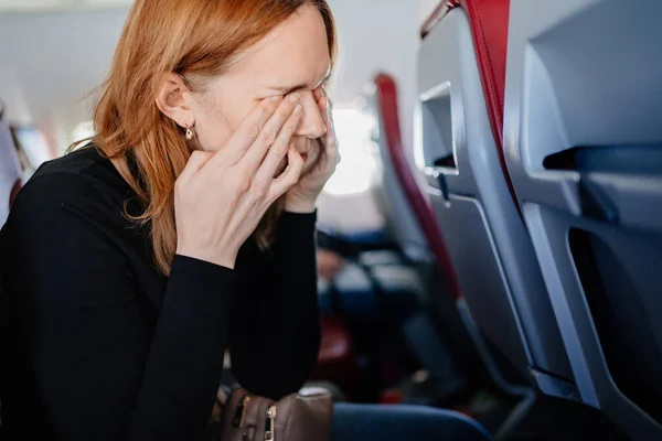 En sömnig kvinna gnider ögonen med händerna i en flygplansstol. långa flygningar. — Stockfoto