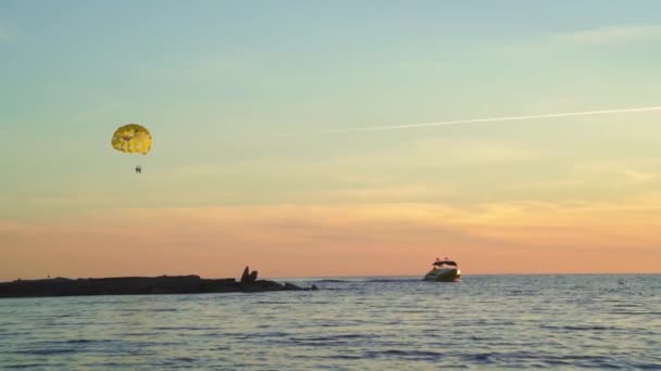 Parasailing is actief type recreatie, persoon op parachute zweeft door de lucht. — Stockvideo