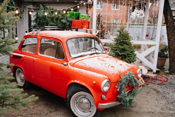 A red little car with a Christmas wreath by the porch of the house. — Stock Photo, Image