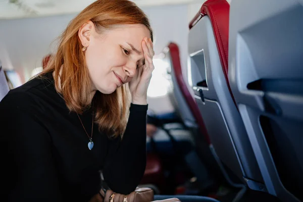 비행기를 타는 여자는 비행기를 타는 동안 두통 이 있다 — 스톡 사진