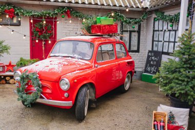 Evin verandasında Noel çelengi olan kırmızı küçük bir araba.. 