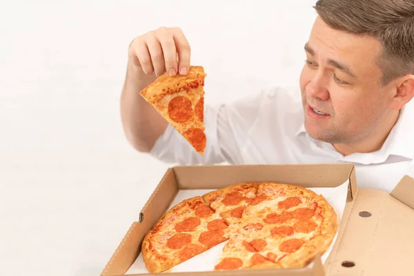 A man in a white shirt holds a slice of pizza with sausage. food delivery — Stock Photo, Image
