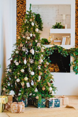 Süslü şöminenin yanında hediye kutularıyla dolu büyük bir Noel ağacı.