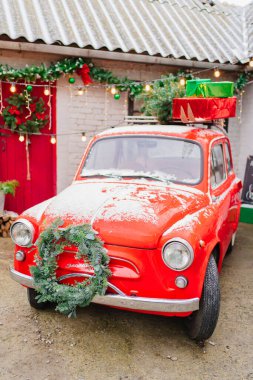 Evin verandasında Noel çelengi olan kırmızı küçük bir araba.. 