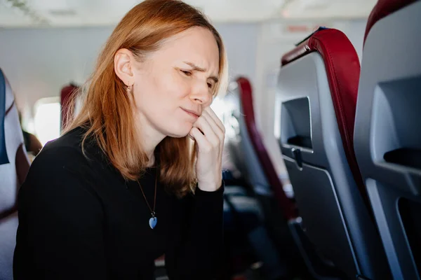在飞机上飞行的女人有牙痛 — 图库照片