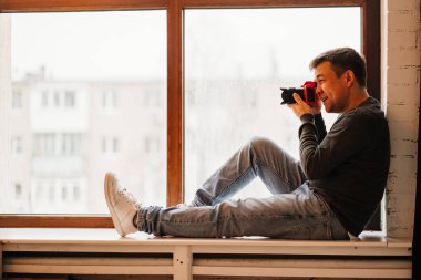 Fotoğrafçı pencere pervazlarına oturur ve fotoğraf çeker. Fotoğraf eğitimi. 