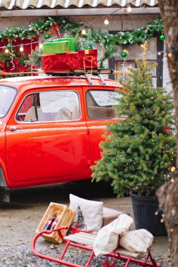 Evin verandasında Noel çelengi olan kırmızı küçük bir araba.. 