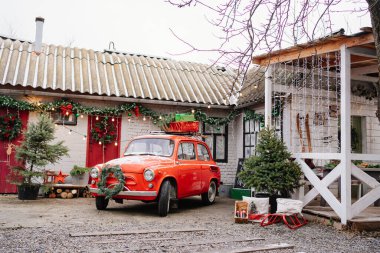 Evin verandasında Noel çelengi olan kırmızı küçük bir araba.. 
