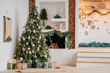 Süslü şöminenin yanında hediye kutularıyla dolu büyük bir Noel ağacı.