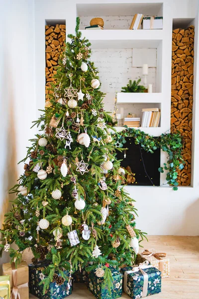 Süslü şöminenin yanında hediye kutularıyla dolu büyük bir Noel ağacı.
