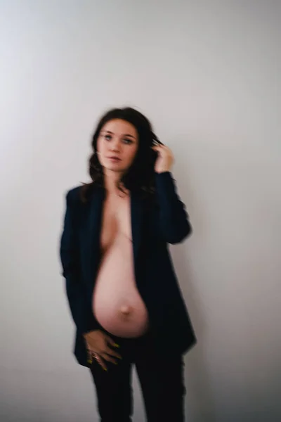 Desenfocar hermosa mujer embarazada en una chaqueta negra con pechos desnudos y vientre —  Fotos de Stock
