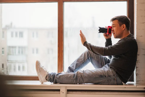 Fotoğrafçı pencere pervazlarına oturur ve fotoğraf çeker. Fotoğraf eğitimi. — Stok fotoğraf