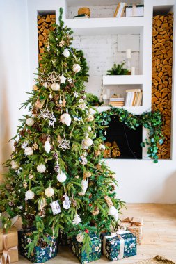 Süslü şöminenin yanında hediye kutularıyla dolu büyük bir Noel ağacı.