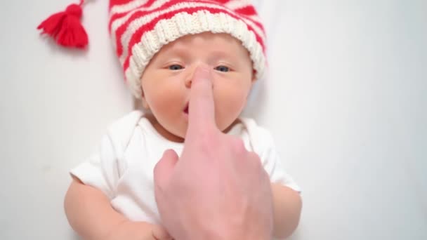Hand touches face of cute little kid in cap of Christmas elf or gnome.baby santa — Stock Video