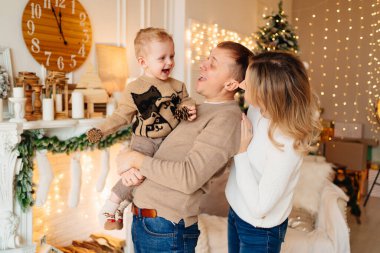 Noel ağacı ve şöminenin yanında küçük bir oğlu olan mutlu bir aile.